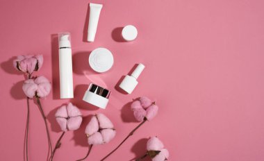 Kozmetik ürünleri için pembe arka planda kavanoz ve boş plastik tüpler. Krem, jel, serum, reklam ve ürün tanıtımı için ambalaj, üst görünüm, kopyalama alanı