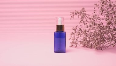 Mavi cam şişe ve pembe arka planda kozmetik ürünleri için bir damlası var. Jöle, serum, reklam ve promosyon için ambalaj. Doğal organik ürünler. Model