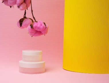 Kozmetik için pembe arka planda beyaz kavanoz. Krem, jel, serum, reklam ve ürün tanıtımı için ambalaj, maket