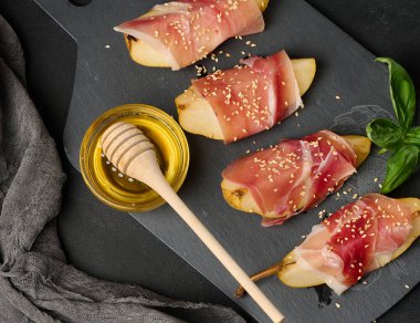 Pear pieces wrapped in thinly sliced ham and sprinkled with sesame seeds