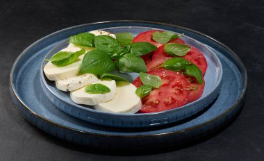 Dilimlenmiş taze domatesli klasik Caprese salatası.