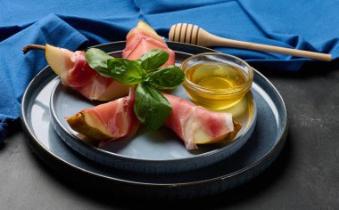 Mavi seramik tabakta armut jambona sarılı gurme aperatifi.