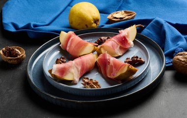 Prosciutto 'ya sarılı armut ve mavi seramik tabakta ceviz..