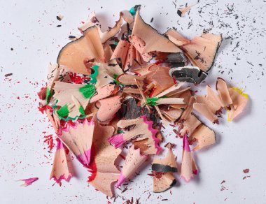 Yukarıdan bakıldığında, beyaz arkaplandaki sivri renkli kalemlerin oluşturduğu sarmal talaş yığınına yakın plan..