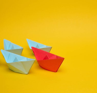 Kırmızı kağıttan bir tekne, üç mavi bottan oluşan bir gruba önderlik ediyor. Liderlik kavramları, rekabet avantajı, kalabalıktan uzak durmak, takım çalışması.