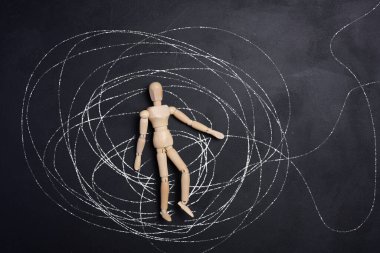 Ahşap, eklemli bir adam figürü tebeşir çizgilerinden oluşan kaotik bir ağın ortasında yatıyor. Kafa karışıklığı kavramları, zor bir durumdan çıkış yolu bulmak ve stres..