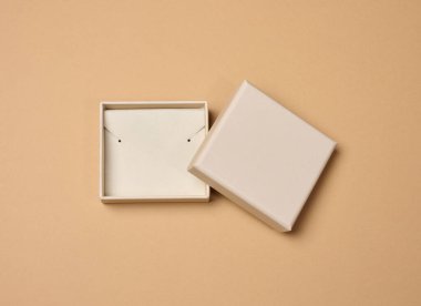 Karton mücevher kutusunu aç, slotlarla birlikte yumuşak iç ekleme, bej arka planda yanında ayrı kapak