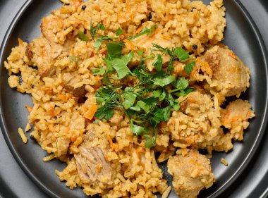 Pirinçli pilav ve masada siyah yuvarlak bir tabakta et parçaları. Lezzetli yemekler.