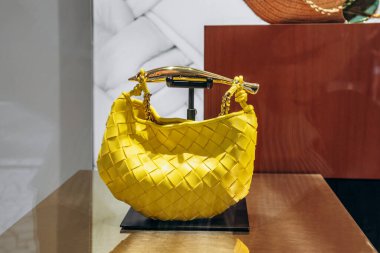 Nice, Fransa - 14 Haziran 2025 Lafayette Galerisi vitrininde sergilenen Sarı Bottega Veneta el çantası