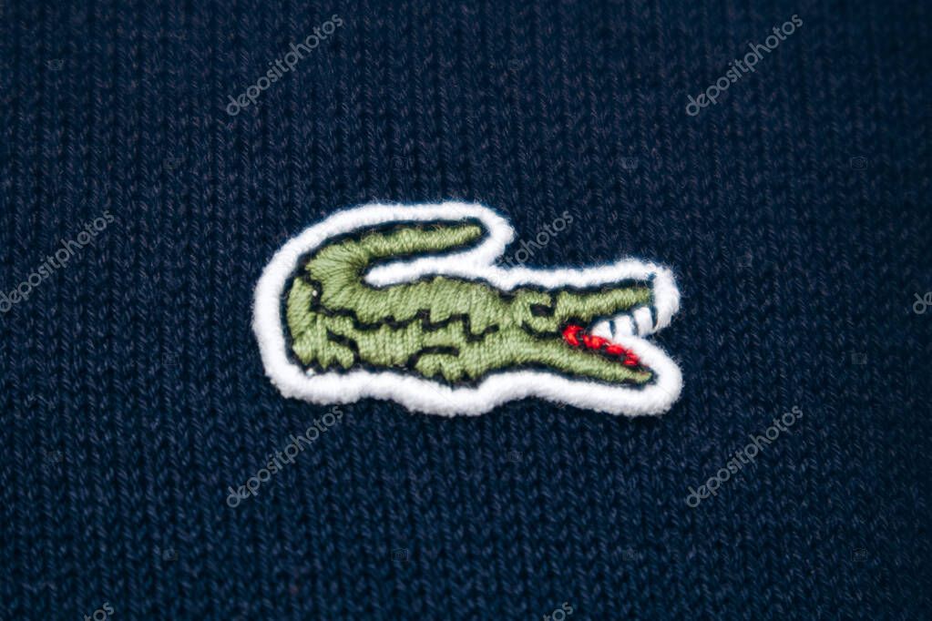 Nice, France - June 14, 2025: Close-up of embroidered Lacoste crocodile logo on navy blue crewneck in boutique