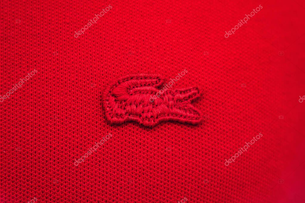 Nice, France - June 14, 2025: Red embroidered Lacoste crocodile logo close-up on polo shirt in boutique