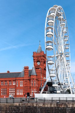 Cardiff, Wales - 14 Ağustos 2022: Güneşli bir yaz gününde tarihi kırmızı Pierhead Binası ve Cardiff Körfezi 'ndeki dönme dolap