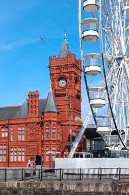 Cardiff, Wales - 14 Ağustos 2022: Güneşli bir yaz gününde tarihi kırmızı Pierhead Binası ve Cardiff Körfezi 'ndeki dönme dolap