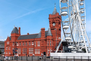 Cardiff, Wales - 14 Ağustos 2022: Güneşli bir yaz gününde tarihi kırmızı Pierhead Binası ve Cardiff Körfezi 'ndeki dönme dolap