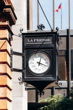 Montreal, Kanada - 11 Ağustos 2025: Eski Montreal 'deki Saint Jacques Caddesi' ndeki antika La Presse saati, tarihi kırmızı tuğla bir binaya iliştirilmiş.
