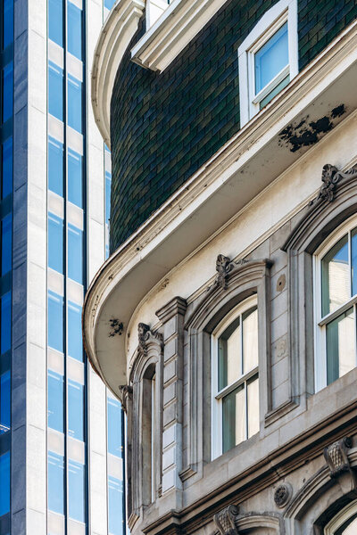 Архитектурные детали фасада исторического здания с современным стеклянным небоскребом в центре Монреаля, Квебек