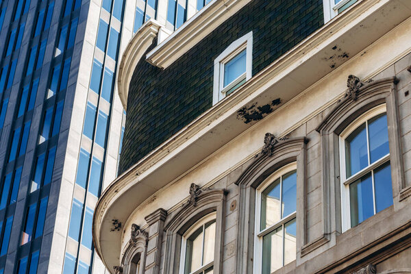 Архитектурные детали фасада исторического здания с современным стеклянным небоскребом в центре Монреаля, Квебек