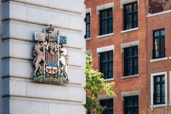 Монреаль, Канада - 11 августа 2025 года: Исторический герб Канады на каменном здании в центре Монреаля с фасадом из красного кирпича на заднем плане