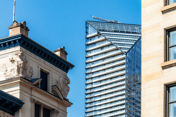 Монреаль, Канада - 11 августа 2025 года: Контраст современного стеклянного небоскреба и исторической архитектуры в центре Монреаля