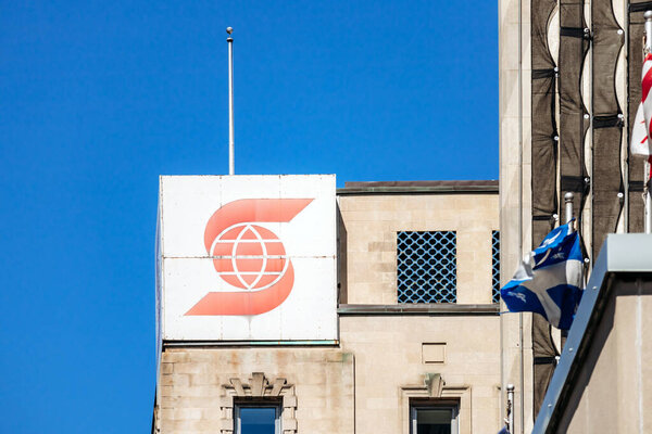 Монреаль, Канада - 11 августа 2025 года: Логотип Scotiabank на фасаде офисного здания в центре Монреаля с флагом Квебека на переднем плане