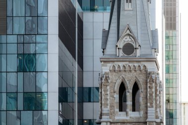 Montreal, Kanada - 13 Ağustos 2025: Saint-Sauveur Kilisesi 'nin tarihi çan kulesi Montreal şehir merkezinin modern cam binaları arasında yükseliyor.