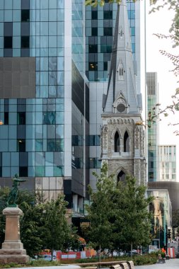 Montreal, Kanada - 13 Ağustos 2025: Saint-Sauveur Kilisesi 'nin tarihi çan kulesi Montreal şehir merkezinin modern cam binaları arasında yükseliyor.