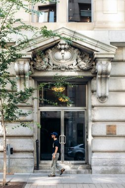 Montreal, Kanada - 14 Ağustos 2025: Süslü mimari detaylara sahip tarihi taş bina cephesi ve Montreal şehir merkezindeki büyük bir girişten geçen bir yaya