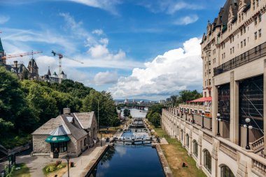 Ottawa, Kanada - 13 Ağustos 2025: Taştan binalar, patikalar ve Ottawa Nehri boyunca yürüyen insanlarla dolu Rideau Kanalı 'nın geniş görüşü
