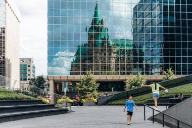 Ottawa, Kanada - 13 Ağustos 2025: Ottawa şehir merkezindeki modern bir ofis kulesinin cam cephesinde tarihi Konfederasyon Binasının yansıması