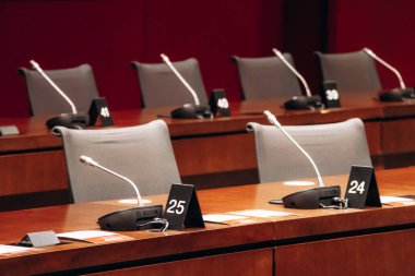 Ottawa, Kanada - 13 Ağustos 2025: Uzun ahşap masalar, mikrofonlar, gri sandalyeler ve bir konferans düzeninde iki Kanada bayrağı bulunan Modern Kanada Senatosu komite odası.