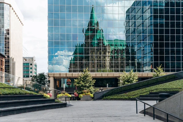 Ottawa, Kanada - 13 Ağustos 2025: Ottawa şehir merkezindeki modern bir ofis kulesinin cam cephesinde tarihi Konfederasyon Binasının yansıması