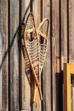 Klasik Quebec kış kültürü ve açık hava mirasını temsil eden kırsal bir kulübenin dış duvarında geleneksel ahşap ayakkabılar sergileniyor..