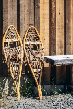 Klasik Quebec kış kültürü ve açık hava mirasını temsil eden kırsal bir kulübenin dış duvarında geleneksel ahşap ayakkabılar sergileniyor..