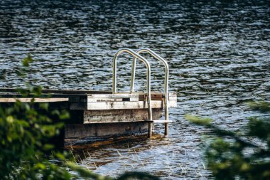 Quebec 'teki La Mauricie Ulusal Parkı' ndaki sakin bir gölün üzerine uzanan metal merdivenli ahşap bir rıhtım.