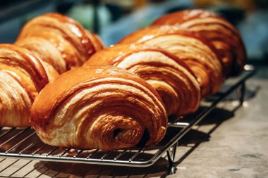 Bir pastane tezgahında sergilenen taze altın kruvasanları kapatın.