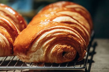 Bir pastane tezgahında sergilenen taze altın kruvasanları kapatın.