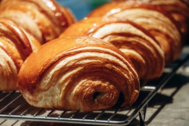Bir pastane tezgahında sergilenen taze altın kruvasanları kapatın.