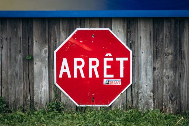 Metabetchouan-Lac-a-la-Croix, Canada - August 19, 2025: Red French stop sign reading Arret mounted on wooden fence with grass at bottom in rural Quebec