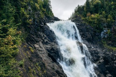 Ouiatchouan Şelaleleri, Quebec 'teki Val-Jalbert Tarih Köyü' ndeki gözlem güvertesiyle yeşil ormandan çağlayarak geçiyor.