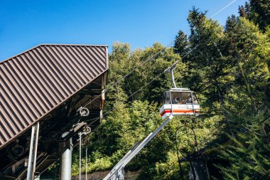 Chambord, Kanada - 18 Ağustos 2025: Quebec 'teki Val-Jalbert Tarih Köyü' nde kablolardan asılı duran beyaz ve kırmızı tramvay