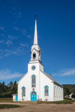 Baie-Sainte-Catherine, Kanada - 21 Ağustos 2025: Mavi kapılı beyaz ahşap kilise ve Quebec 'in Capitale-Nationale bölgesinde açık gökyüzü altında uzun çan kulesi