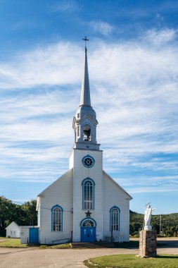 Baie-Sainte-Catherine, Kanada - 21 Ağustos 2025: Mavi kapılı beyaz ahşap kilise ve Quebec 'in Capitale-Nationale bölgesinde açık gökyüzü altında uzun çan kulesi