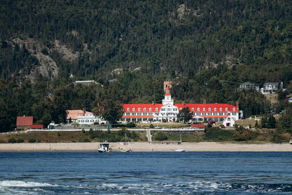 Saguenay Nehri 'nin karşısındaki panoramik manzara ikonik kırmızı çatılı otel Tadoussac' ı gösteriyor..