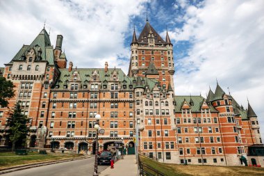 Quebec City, Kanada - 23 Ağustos 2025: Fairmont Le Chateau Frontenac şatosu oteli Terrasse Dufferin rıhtımına bakan taretler, taş duvarlar ve yaz günü gezinen turistler