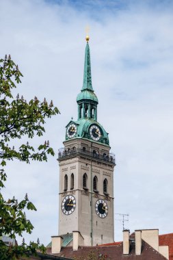 Münih, Almanya - 15 Nisan 2025: Tarihi saati ve eski Münih, Bavyera, Almanya 'daki yeşil bakır kulesi ile Aziz Peter Kilisesi kulesinin görüntüsü