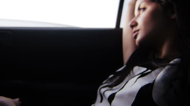 Νέοι κορίτσι που αναζητούν έξω από το παράθυρο του αυτοκινήτου κατά το ηλιοβασίλεμα — Αρχείο Βίντεο