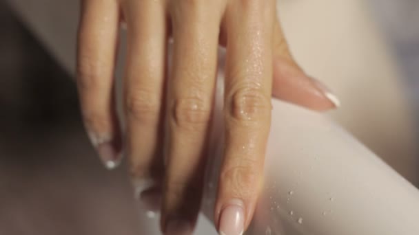 Gotas de agua en la muñeca de la mujer con manicura en cámara lenta sobre un fondo blanco — Vídeo de stock