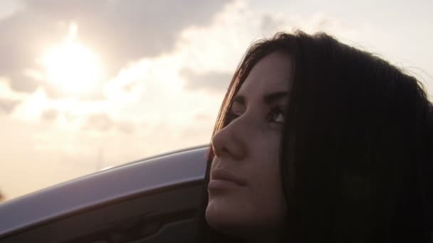 Junges Mädchen starrt und posiert neben dem Auto auf dem Himmelshintergrund — Stockvideo