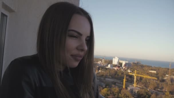 Blondine lächelt in die Kamera und sonnt sich im Hintergrund der Stadt — Stockvideo