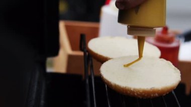 Adam aşçı hamburger hardal çörekler sıcak ızgara üzerinde yaz aylarında dökme